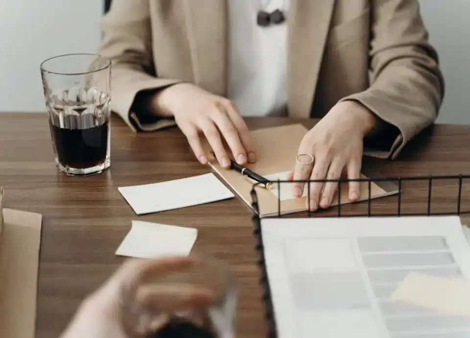 Hands organizing a folder and paperwork on a desk.