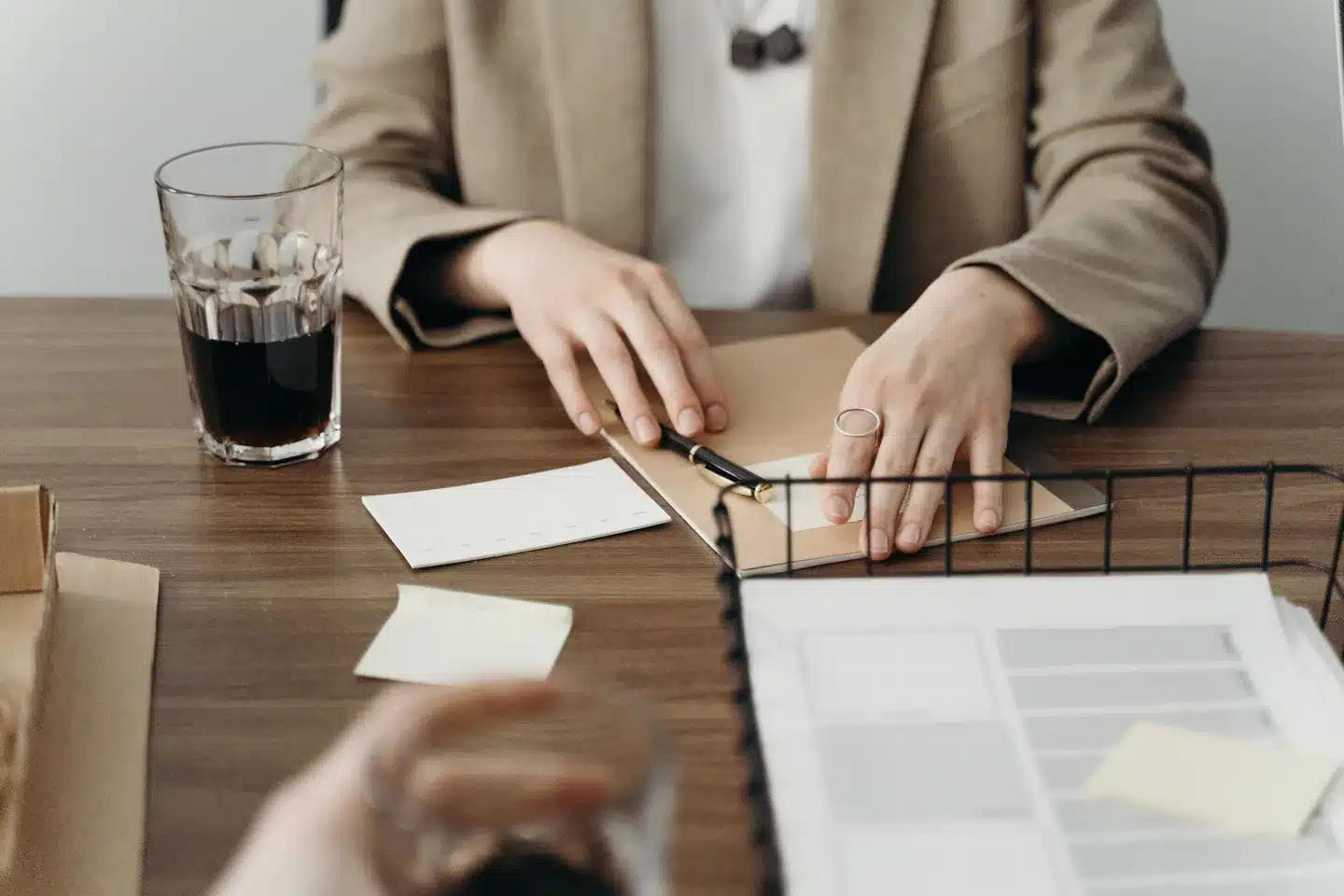 Hands organizing a folder and paperwork on a desk.